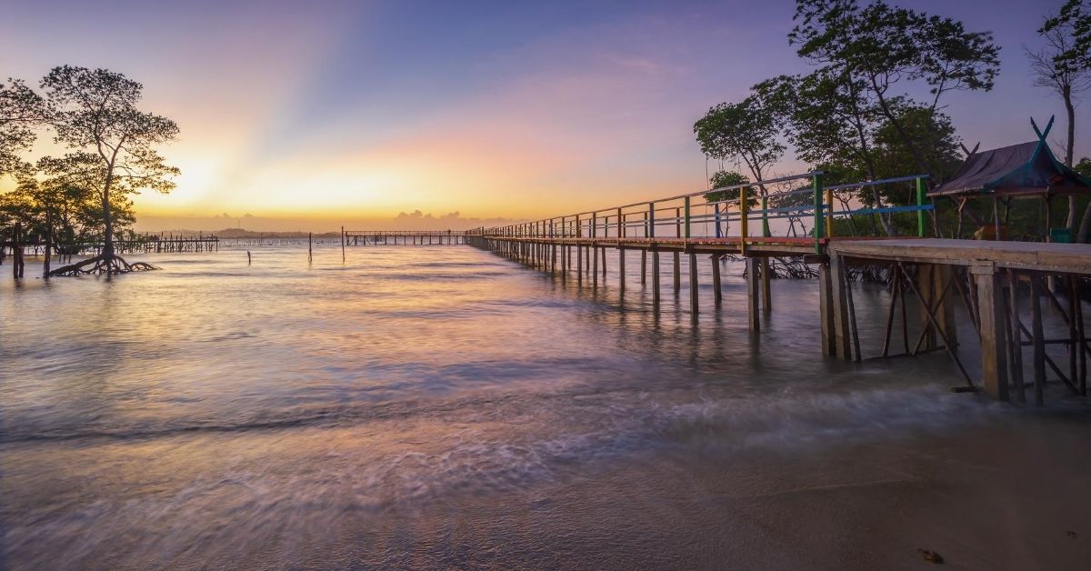 a jetty over the water at sunset with trees in Batam Bintan