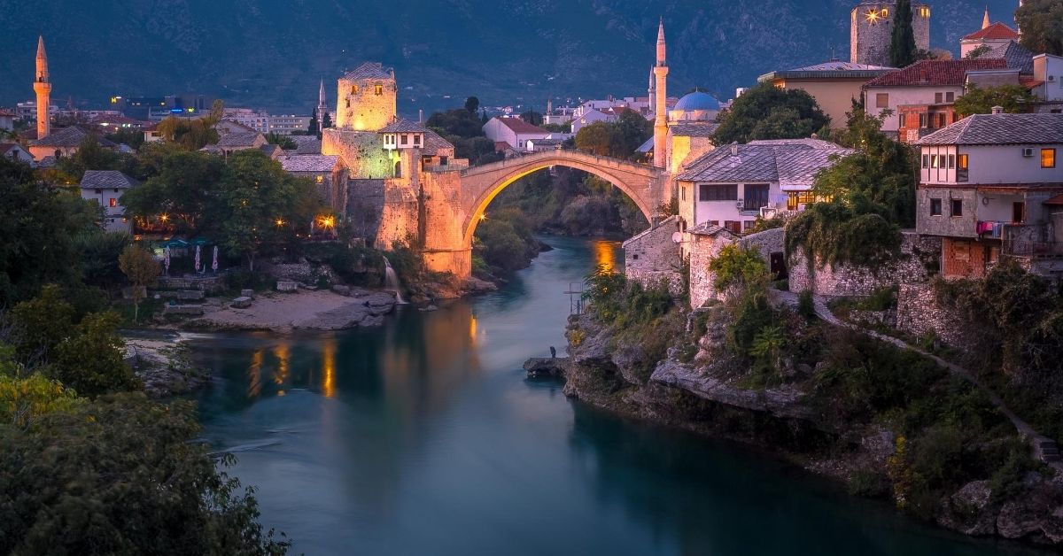 famous Stari Most bridge at dusk with surrounding village on river in Mostar