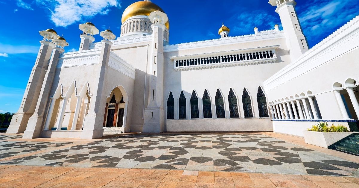 White mosque with gold a gold dome and minarets against a blue sky
