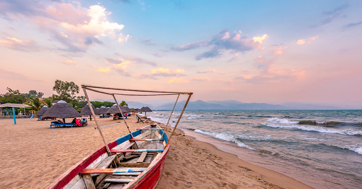 wooden boat along the sandy resort beach of Lake Tanganyika with mountains in the distance