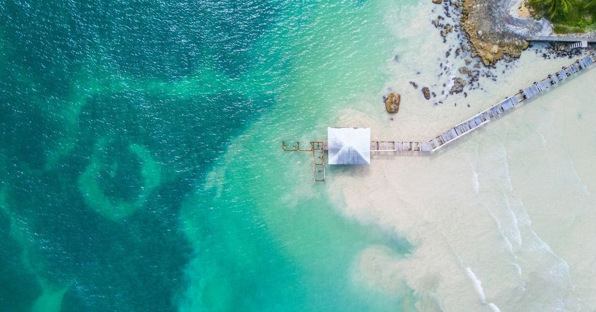 bird's eye view of jetty extending out over the Caribbean with shades of aquamarine