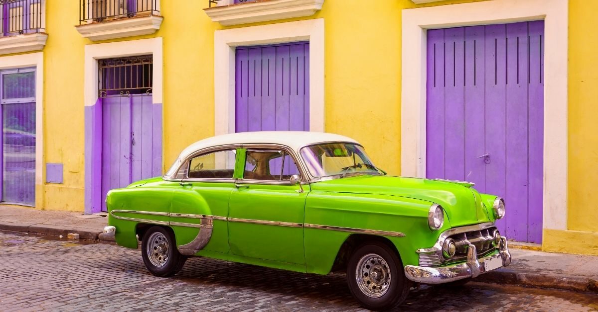 lime green 1950's car in front of yellow building with purple doors in Cuba