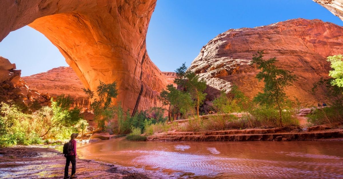 hiker surrounded by red sandstone formations at Coyote Gulch, Grand Staircase-Escalante National Monument in Utah