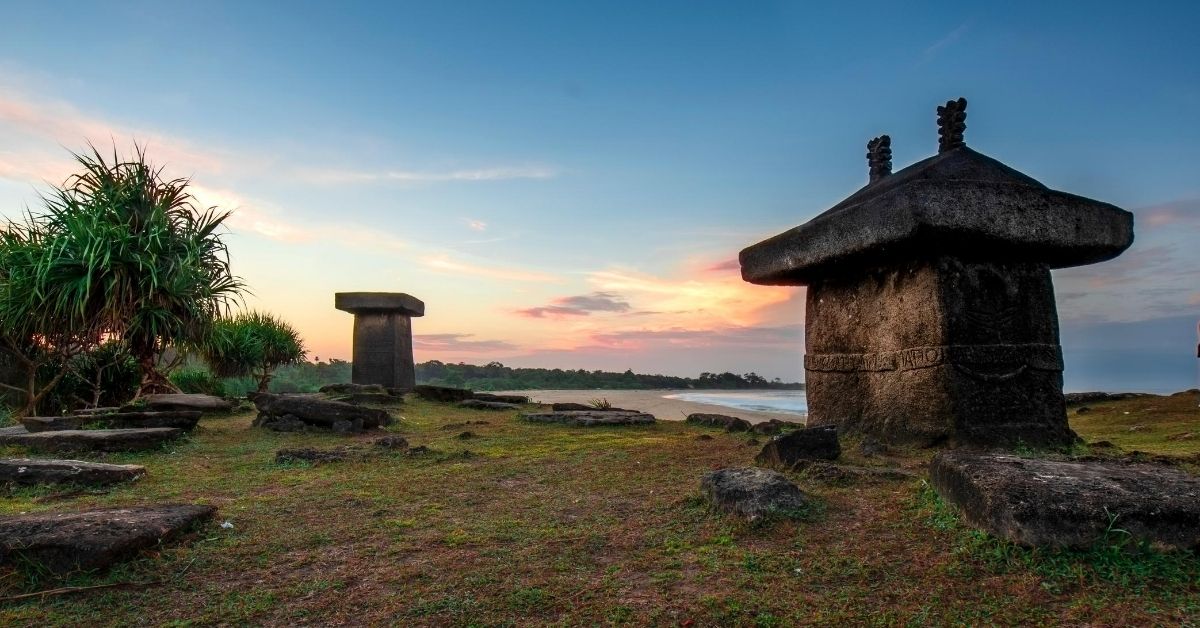 Megalithic Tombs on a beach surrounded by tropical greenery at sunrise