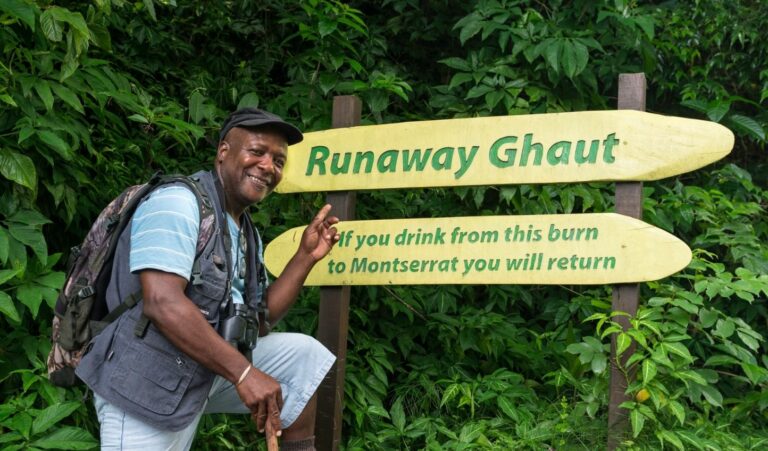 a scribe points to a sign for Runaway Ghaut in Montserrat