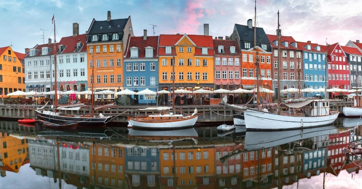 colorful buildings on wharf with sailboats at sunrise in Nyhavn, Copenhagen, Denmark