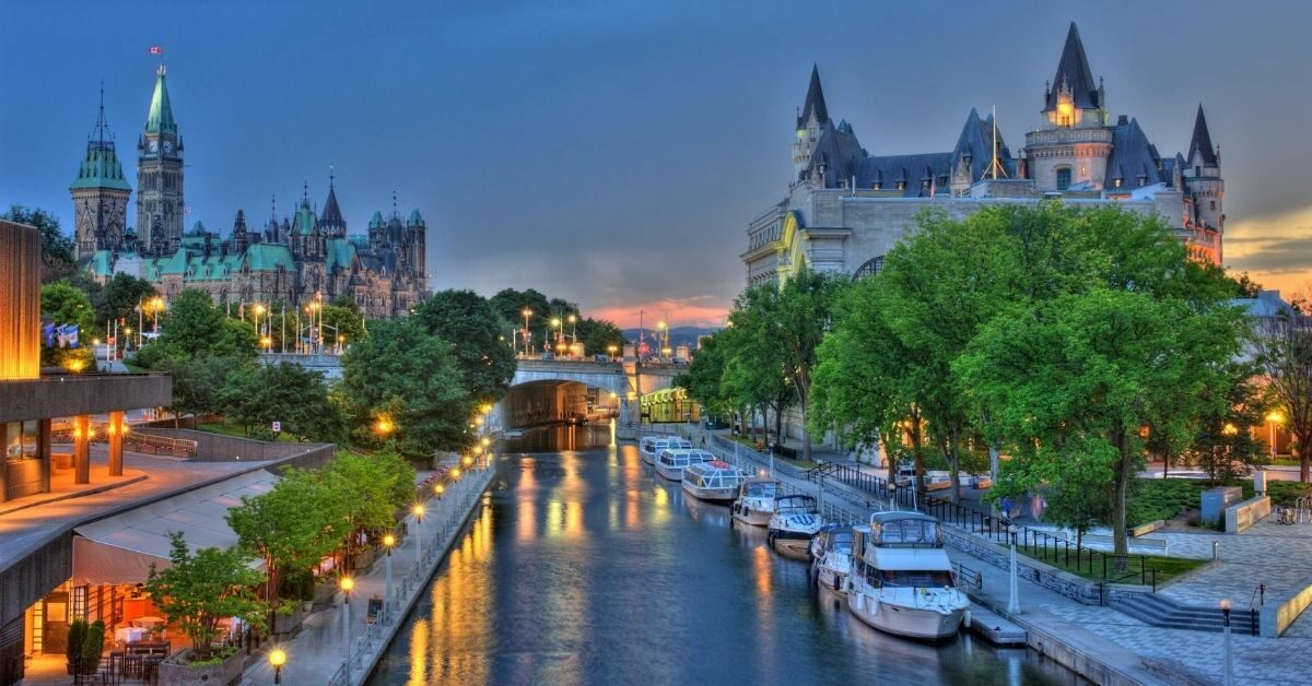 illuminated canal with boats and Gothic architecture on either side at sunset with reflections of light in the water