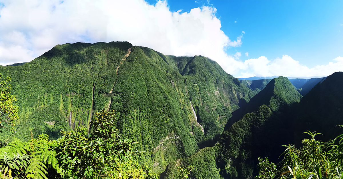 green mountains on Réunion island with waterfalls and cloudy blue skies