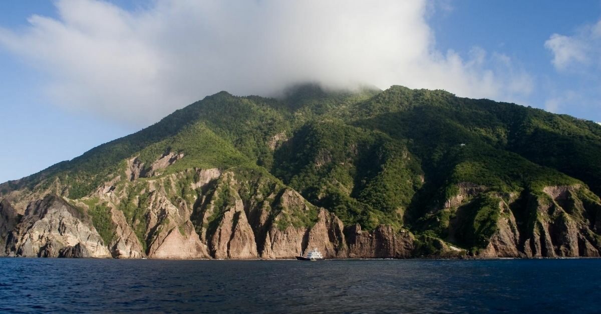 coast of Saba island jagged cliffs and green mountains with boat