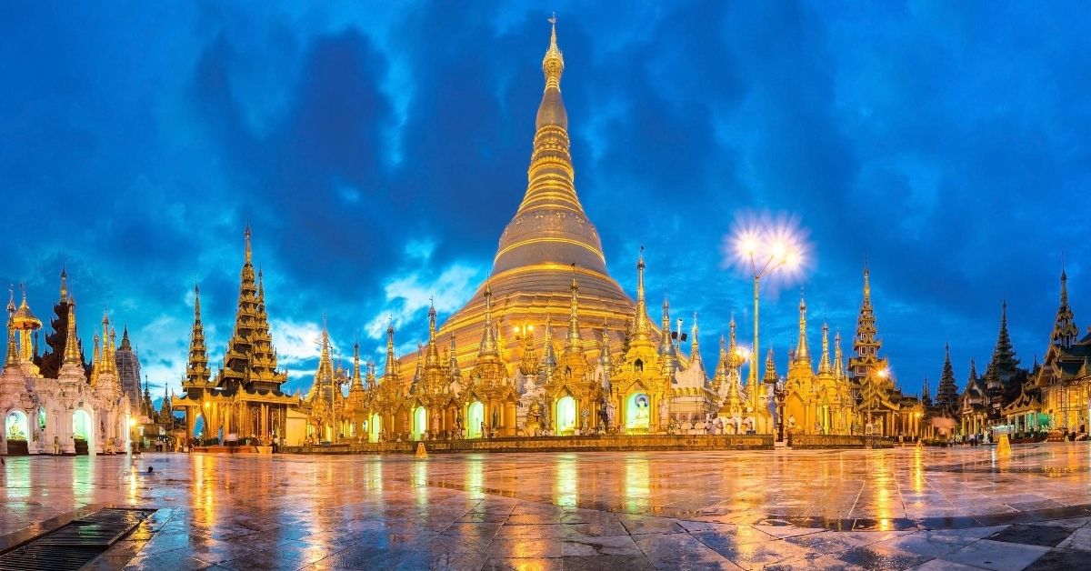 ornate temples with gold stupa illuminated at dusk and reflected in marble