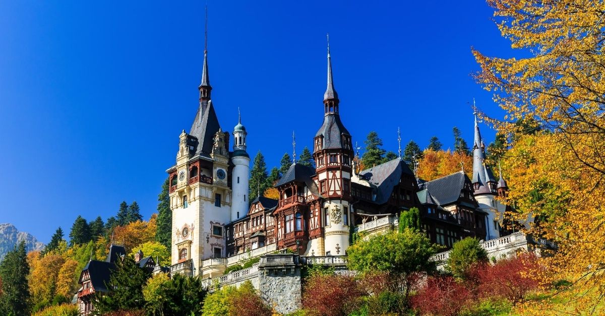 medieval castle on hill against perfect blue sky and fall colored foliage