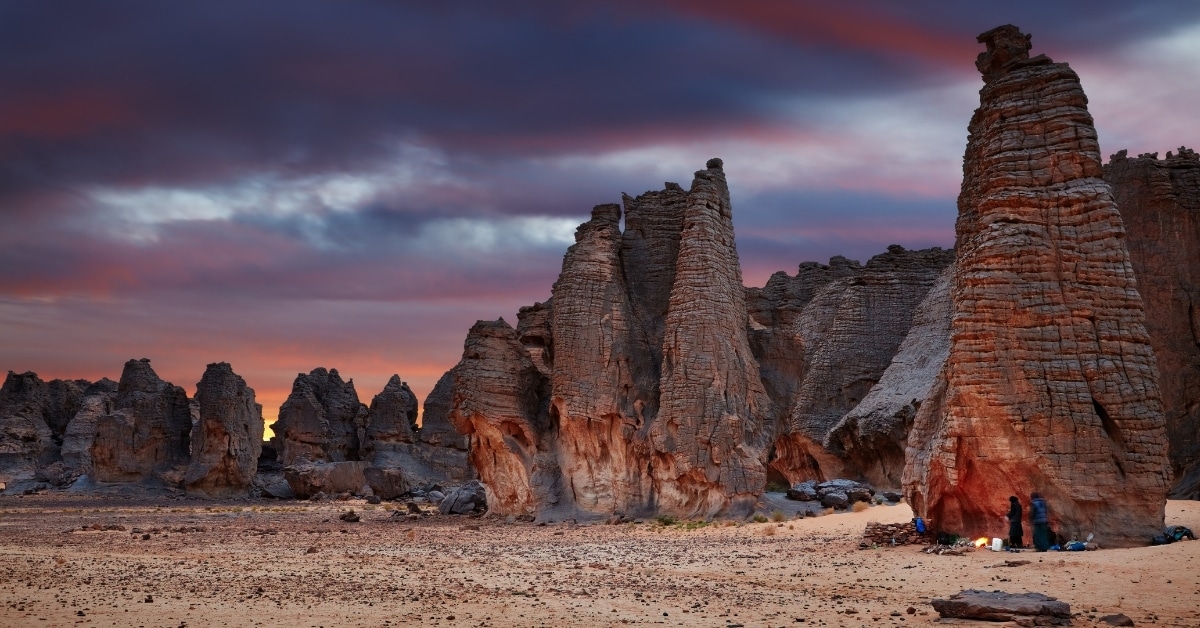 people with unusual rock formations at Tassili-n'Ajjer in Algeria as the finally sun sets