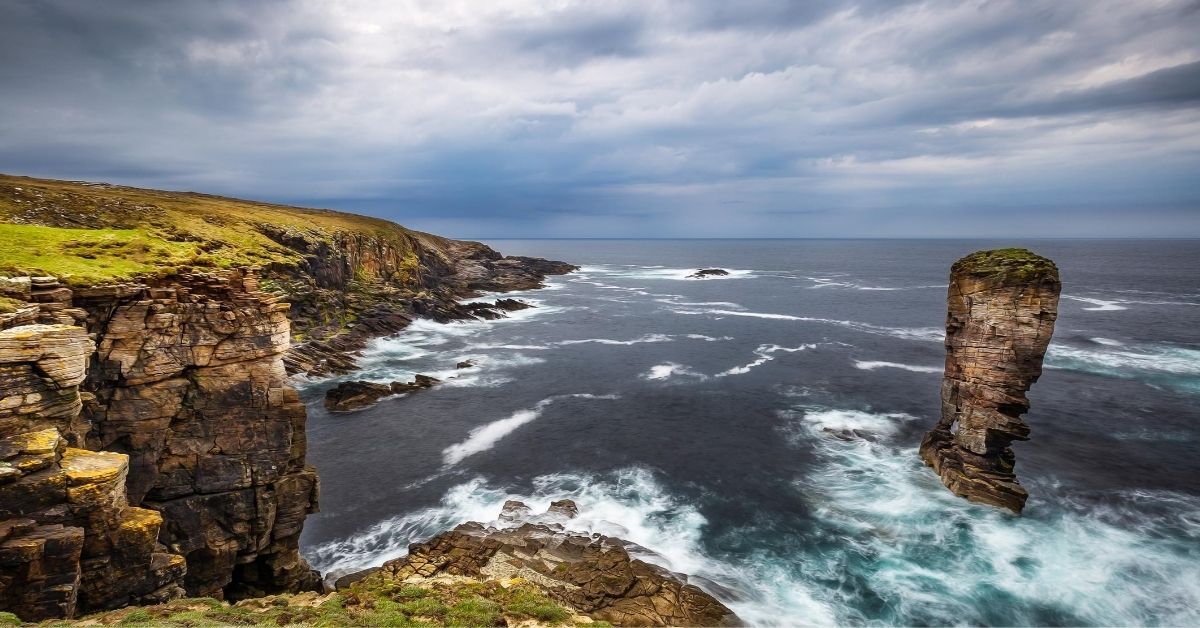 coastal cliffs and rock formation in the Orkney Islands on an overcast day with surf washing in from the Atlantic