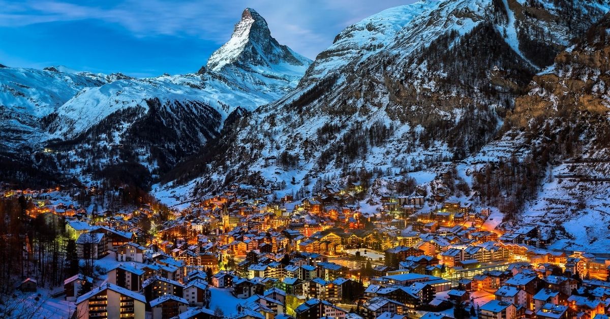 Bird's eye view of the snow covering Zermatt Valley with buildings illuminated and Matterhorn mountain in the background