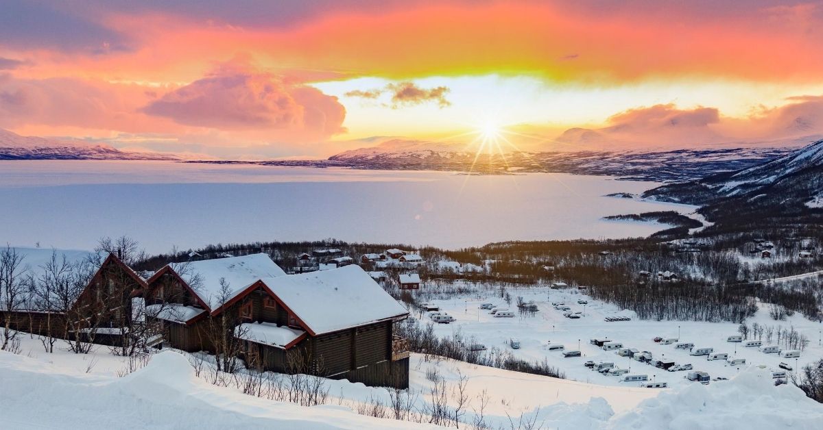 village with snow covered landscape at sunrise with mountains