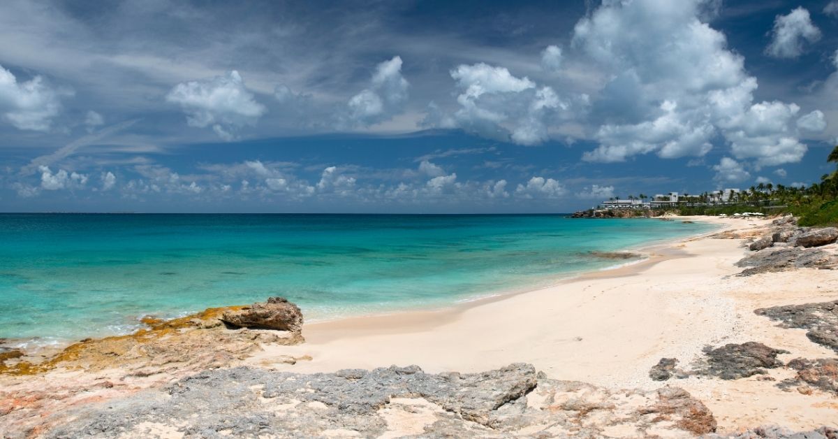 beautiful beach in Anguilla with cloudy skies above and hotel in the distance