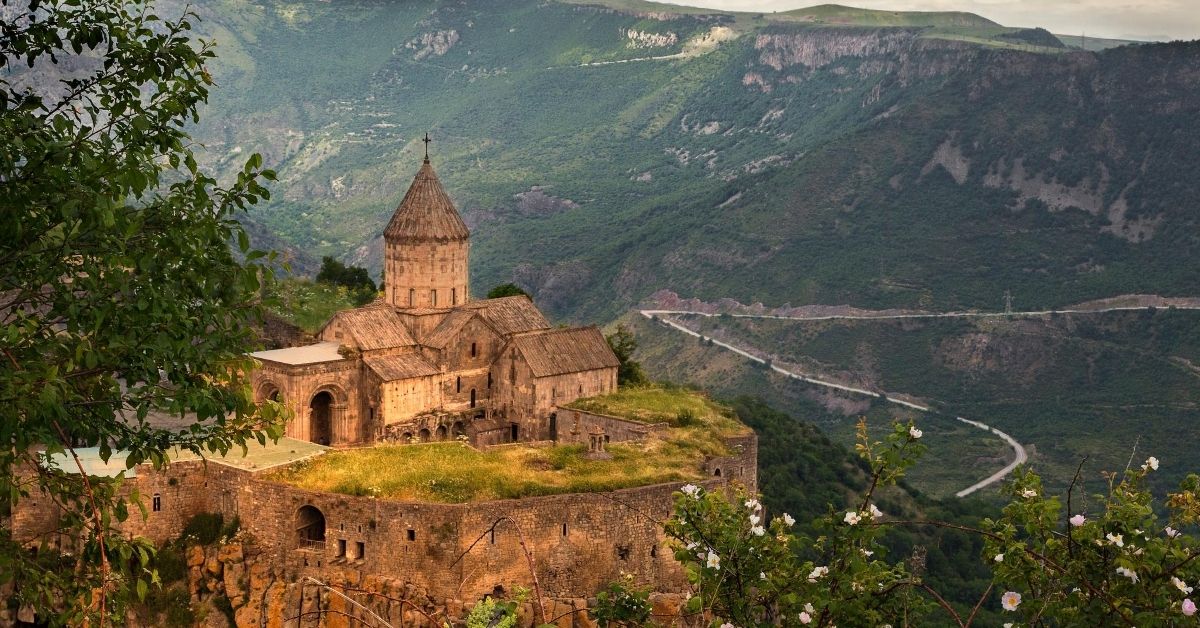 historical cathedral nestled in the mountains in Armenia with snake like road and greenery