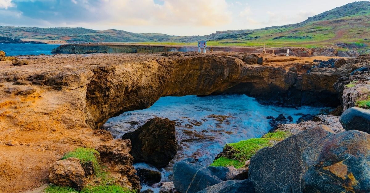 natural stone bridge with a small sea pool along a rocky coast in Aruba