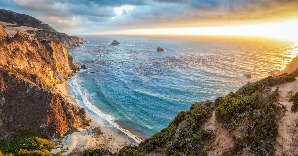 dramatic cliff faces with beach below at sunset