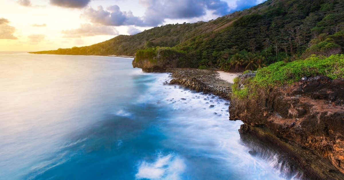 lush rainforest on remote Pacific island at dawn with rocky deserted beach