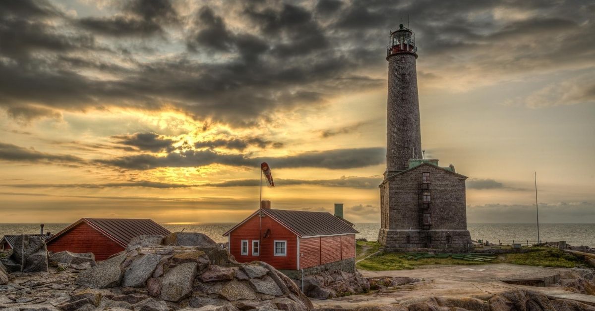 lighthouse with red out buildings with a cloudy sunset