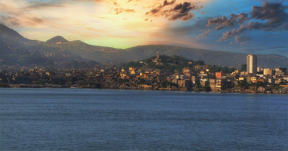 Freetown, a coastal city in Sierra Leone with buildings at sunset coming down over the hills viewed from the Atlantic Ocean