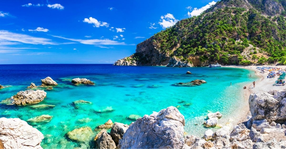 Beach enclave between rocky mountains on Karpathos Island with turquoise waters of the Mediterranean on a sunny day