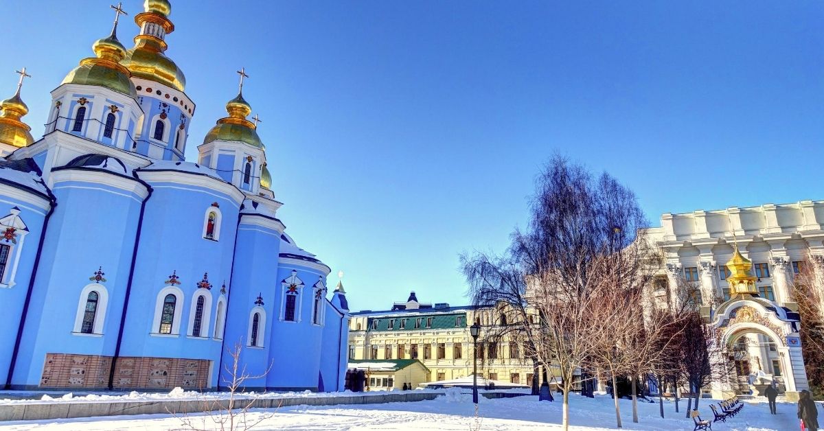 Kiev square with blue church with gold spires and other buildings in the winter