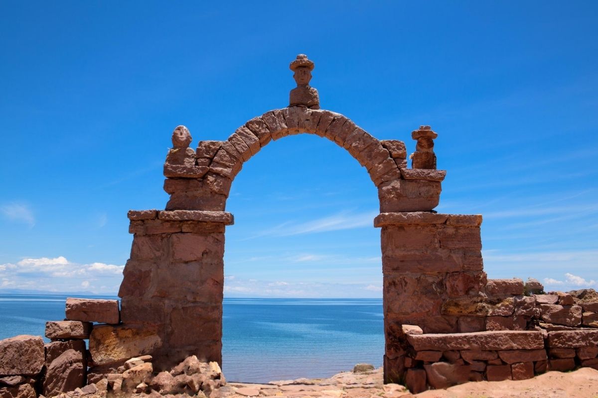 ancient arch with human figures on hillside overlooking lake Titicaca