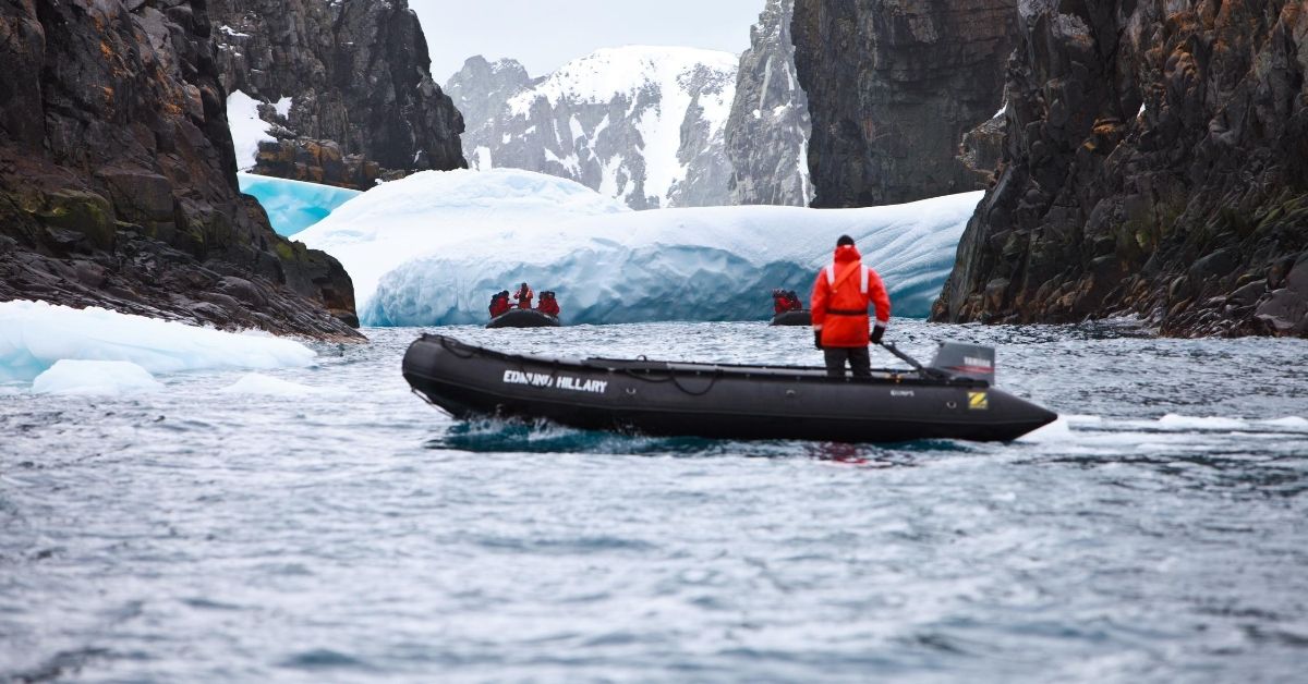 tourists exploring by zodiac boats in the South Shetland Islands with mountains and ice
