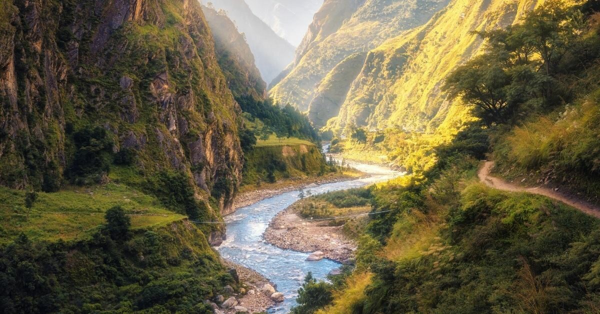 Himalayan deep mountain gorge with stream and sunlight shining in