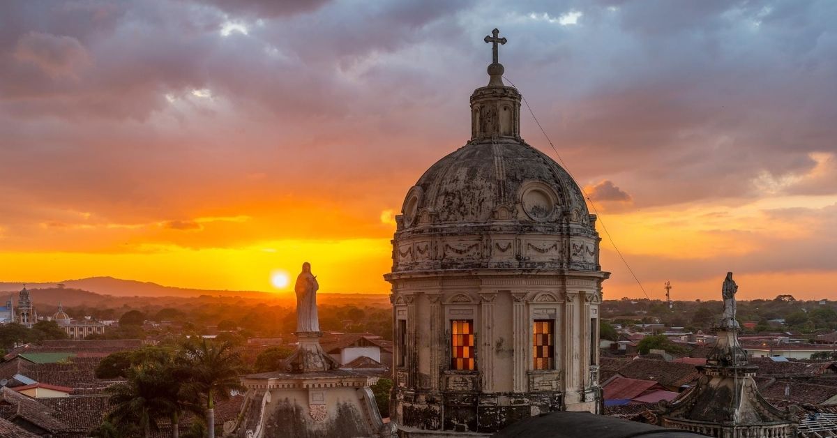 Central America has beautiful colonial cities like Granada, Nicaragua as seen here with this view from a church tower at Sunset with a domed tower and statues looking out and down into the city