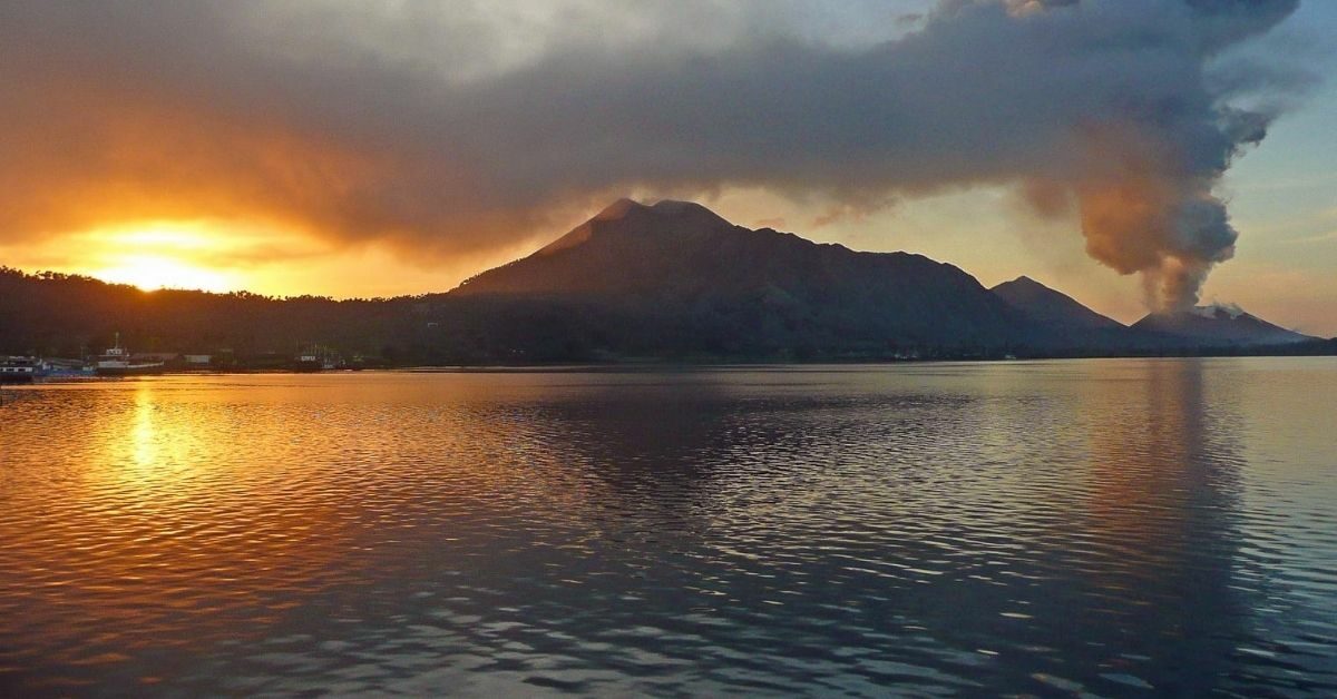 landscape of island with smoking volcano at sunrise viewed from the Pacific