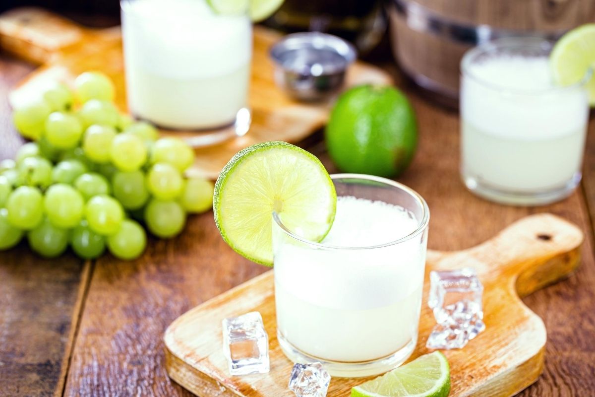 a refreshing cocktail with ice, lime and grapes on a wooden table