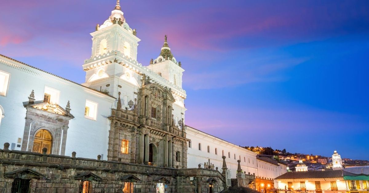 the white-washed colonial San Francisco Church in old town Quito at dush with purplish blue sky