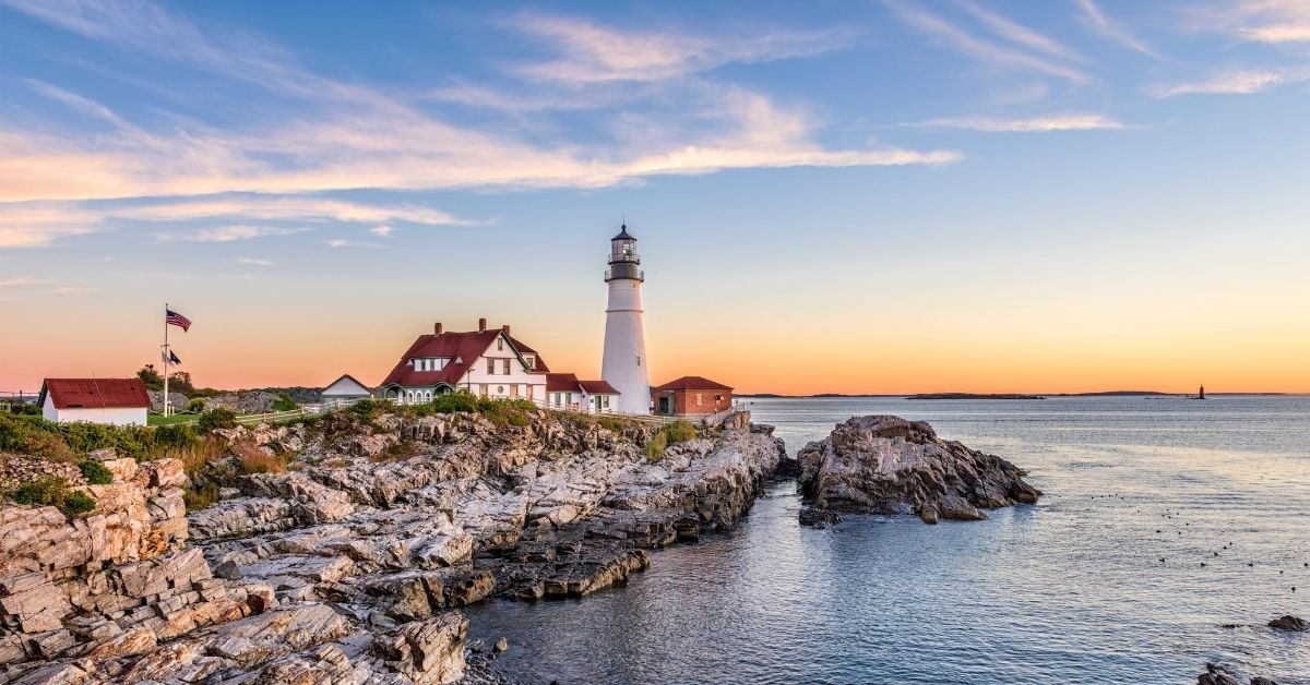 lighthouse and outer building on rocks facing the Atlantic in Portland, Maine at sunset