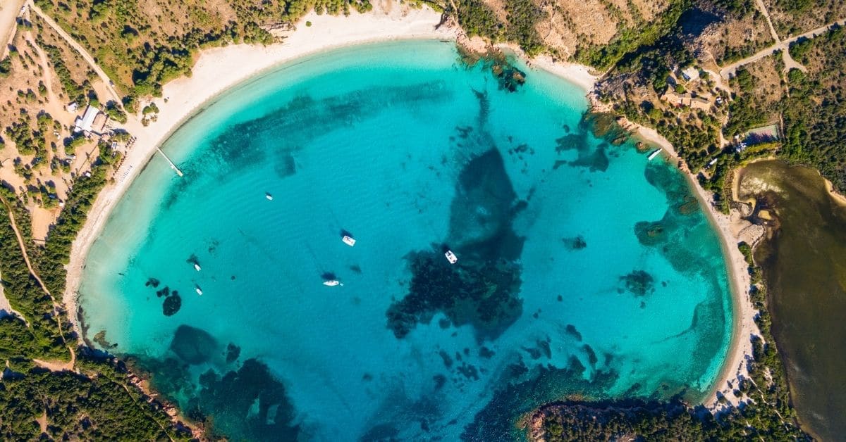 bird's eye view of Rodinera Beach with boats in the bay, Corsica