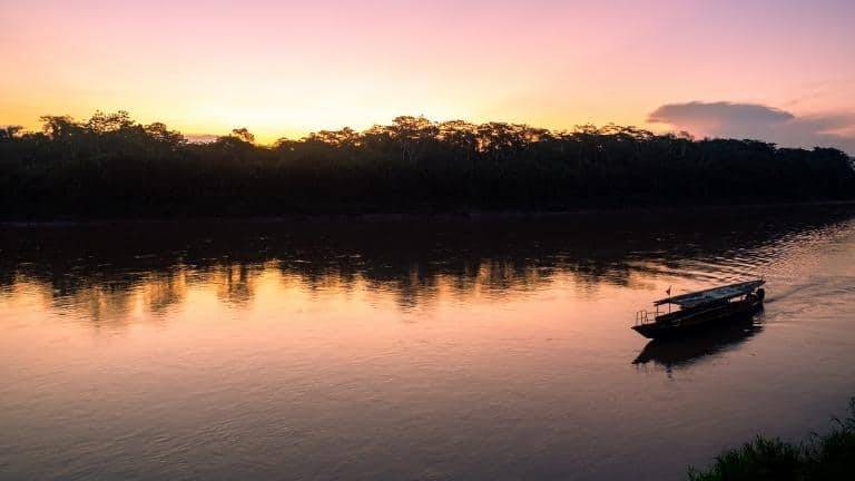 a motorized canoe on river at sunset