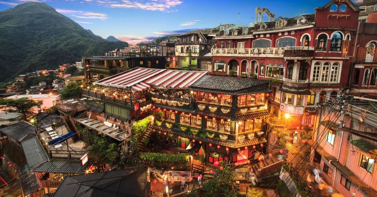 several stories of traditional tea houses built into the surrounding hills illuminated at twilight