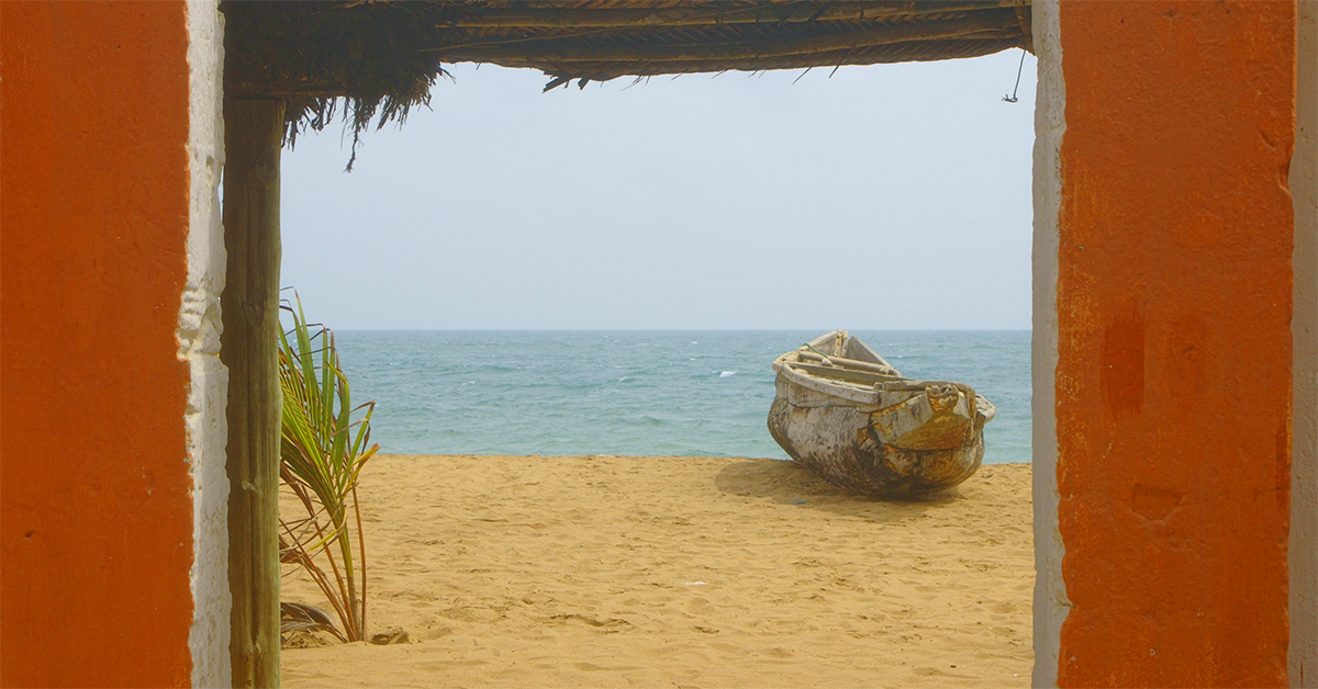 view to the Atlantic Ocean and wooden boat framed by a orange doorway