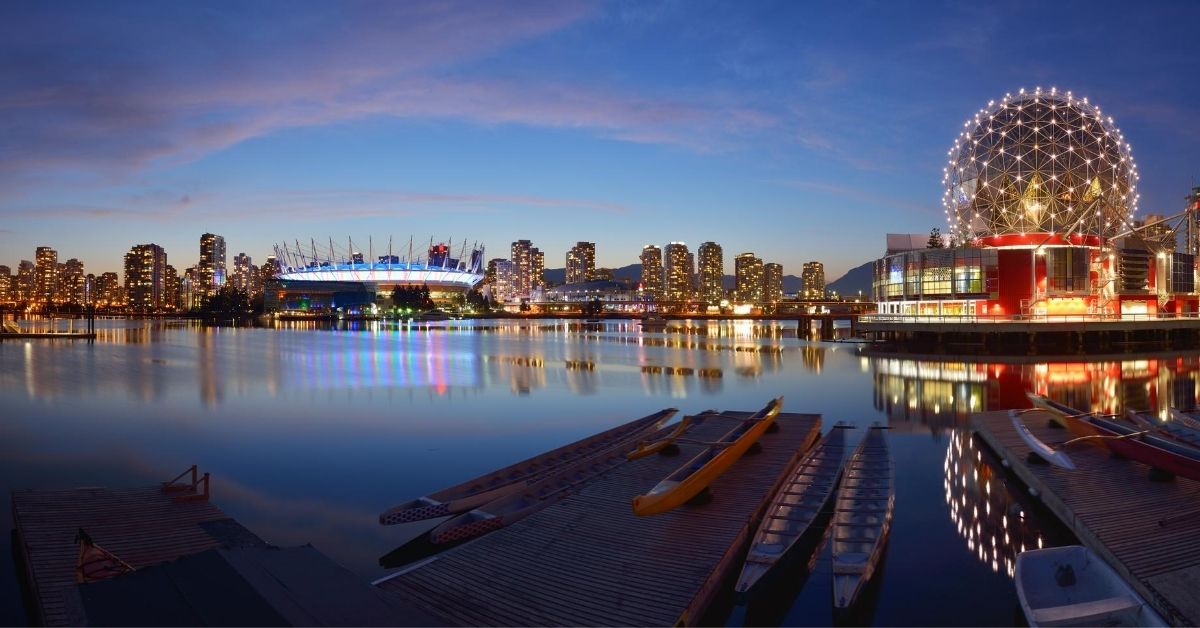 colorful view of Vancouver skyline from docks illuminated by lights at dusk